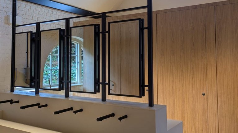 A row of sinks with mirrors above and wooden cubicle doors behind